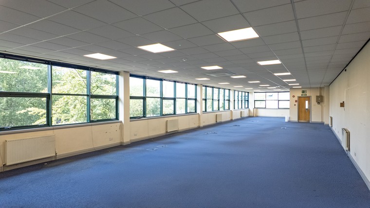 A long open plan first floor office with a continuous window run